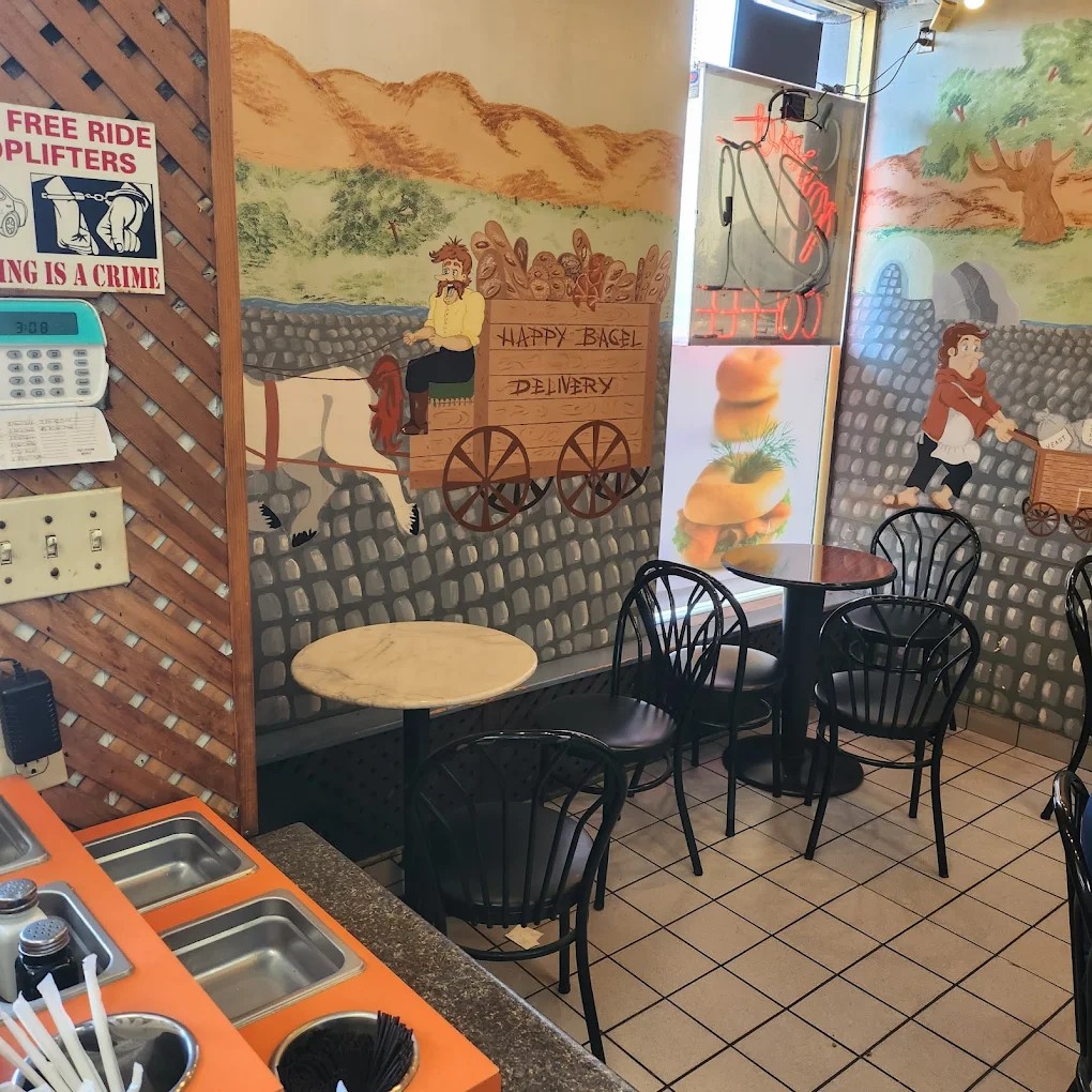 Seating area with hand-painted mural of a horse-drawn wagon labeled Happy Bagel Delivery.